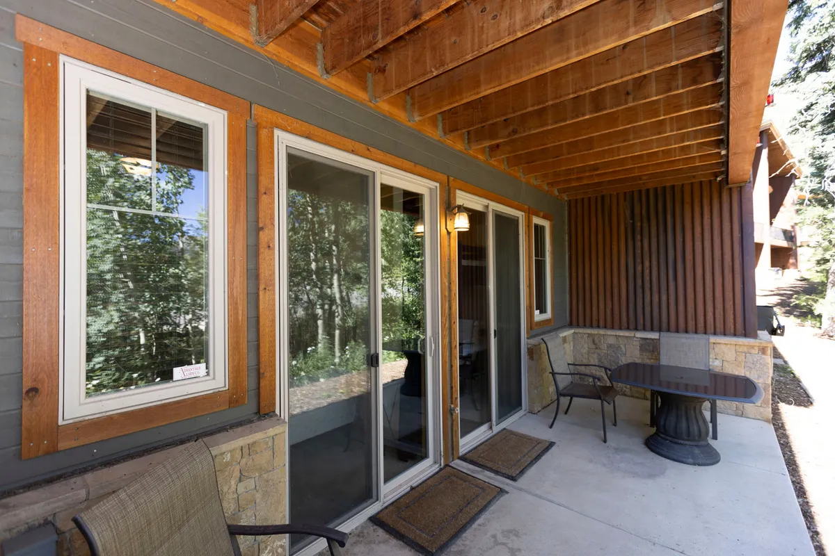 An exterior shot showcasing large glass doors, an outdoor seating area, and overhead wooden beams. The image hints at easy access in and out for ski-in/ski-out convenience and provides a sense of the dedicated entry area and seamless indoor-outdoor flow.